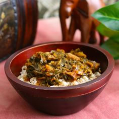 a bowl filled with rice and vegetables on top of a pink table cloth next to an elephant figurine