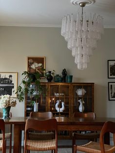 the dining room table is surrounded by chairs and vases with flowers in them on display