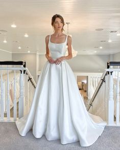 a woman in a white wedding dress standing on the stairs with her hands on her hips