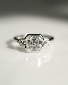 an engagement ring with three stones on it sitting on a white countertop in front of a mirror