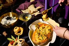 a person is eating food from a bowl on a table with other foods and condiments