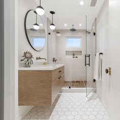 a bathroom with white tile and wood accents, along with an open shower door that leads to a walk - in shower