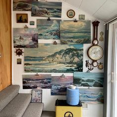 a living room filled with lots of paintings on the wall next to a gray couch