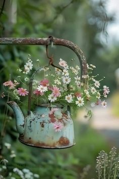 an old watering can with flowers growing out of it