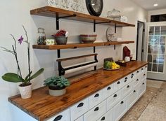 a kitchen with white cabinets and wooden shelves