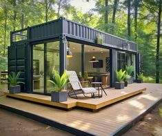 a house made out of shipping containers in the middle of a wooded area with chairs and tables