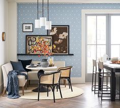 a dining room with blue wallpaper and white chairs in the corner, next to a round table