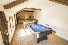 a pool table in the middle of a room with wood flooring and exposed beams