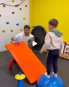 a man and a boy playing with an inflatable ball at the playroom