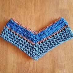 a crocheted blue and pink piece of cloth sitting on top of a wooden table