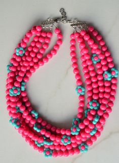 A beaded multi strand statement necklace made with hot pink round acrylic beads and turquoise and pink flower beads.- Shortest strand measures 18.75-20.75" long (length can be customized)- 6 Strands (more are listed)- 10mm ad 12mm beads- Stainless steel lobster claw clasp (sterling silver, gold filled and gold stainless steel also available)- Stainless steel 2" extender chain- Lead Free pewter connectorFor your reference, the mannequin's neck size is 14.5".A matching bracelet and earrings are av Turquoise And Pink, Silver Jewelry Box, Chunky Statement Necklace, Pink Round, Turquoise Flowers, Chunky Beads, Matching Bracelet, Flower Beads, Pink Turquoise