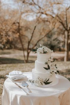 a wedding cake sitting on top of a table next to a knife and fork in front of it