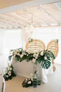 an arrangement of flowers and greenery in vases on the floor next to chairs