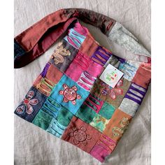 a multicolored patchwork purse sitting on top of a bed