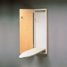 an open door with a surfboard hanging from it's side in front of a gray wall