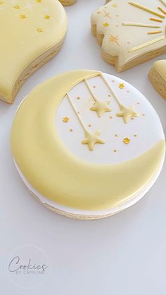 cookies decorated like the moon and stars on a white table with other cookies in the background