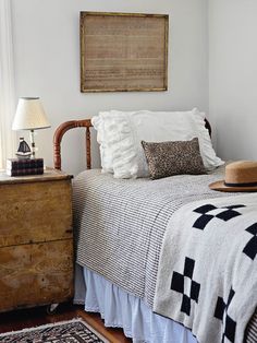 a bed sitting next to a wooden dresser in a room with two lamps on top of it