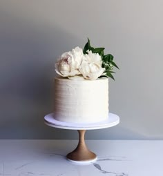 there is a white cake with flowers on the top and bottom, sitting on a stand