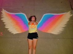 a woman with wings painted on her body is standing in front of the camera and taking a photo