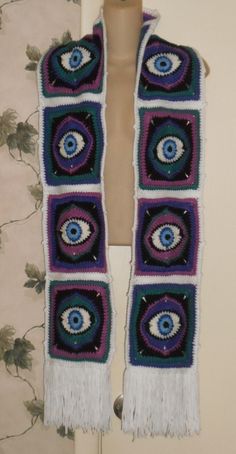 a crocheted scarf with an evil eye on it