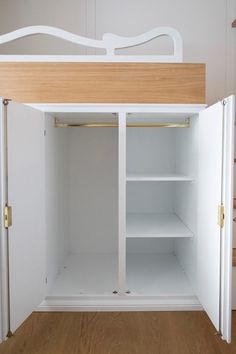 an open white cabinet with shelves and drawers on the bottom shelf, in front of a wooden floor