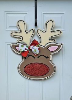 a door hanger with a reindeer's head and red bow on the front