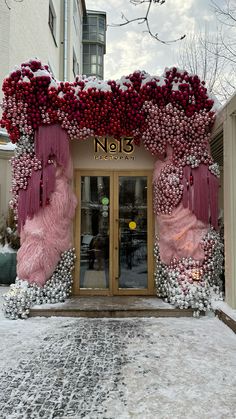 an entrance to a store decorated with pink and white flowers in the snow on a snowy day