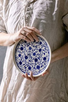 a woman holding a blue and white plate in her hands