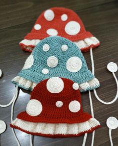 three crocheted hats sitting on top of a wooden table next to white circles