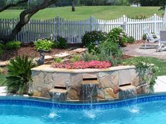 a backyard with a pool and waterfall in the center, surrounded by flowers and trees