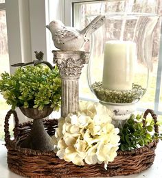 a basket filled with flowers and candles sitting on top of a table next to a window