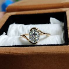 an engagement ring is in a box with white cloth on the bottom and gold band