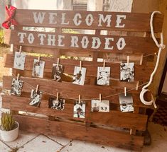 a welcome to the rodeo sign with pictures hanging on clothesline and cactus in pot