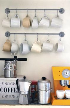 there are many cups hanging on the wall above the coffee maker and other kitchen items