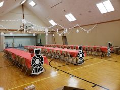 a room filled with tables and chairs covered in red tablecloths, decorated with train decorations