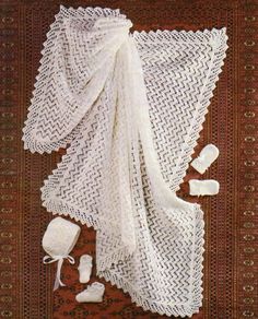 the white crocheted shawl is laid out on top of a red rug