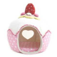 a pink and white cat bed with a strawberry on top in the shape of a castle