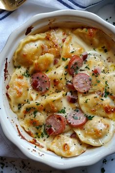 a white bowl filled with pasta covered in cheese and sausages on top of a table