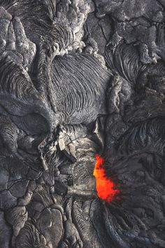 an aerial view of lava and rocks with a bright orange substance in the foreground