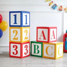 children's blocks with numbers and letters are sitting on the floor in front of balloons