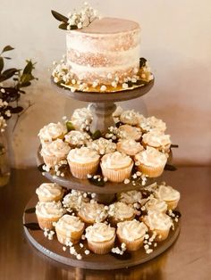 three tiered cake and cupcake display on wooden table