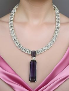 Lustrous Pink CZ stone with crystal-work combines with a delicate White gold frame to immediately effuse any ensemble with a dramatic dose of evening elegance! The set includes a pair of matching dangle earrings. Available in Pink and Amethyst Purple Dimension: 7" long, 2.25" pendant, 2.25" earrings Weight: 2.8 oz, w/ packaging 3.5 oz Luxury Purple Diamond Necklace, Purple Cubic Zirconia Necklaces For Party, Luxury Purple Jewelry For Party, Purple Luxury Jewelry For Party, Purple Cubic Zirconia Necklace For Formal Occasions, Purple Diamond Necklaces For Wedding, Purple Diamond Necklace With Diamond Accents, Silver Amethyst Necklaces For Party, Purple Gemstone Necklace In Cubic Zirconia