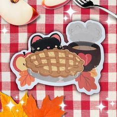 an apple and some stickers on a red checkered table cloth with autumn leaves