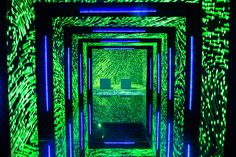 an illuminated room with green and blue lights on the walls, in front of a mirror