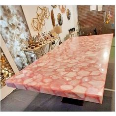 a large pink marble table top in a room with pictures on the wall behind it