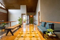 a long hallway with yellow and white tiles on the floor, potted plants next to it