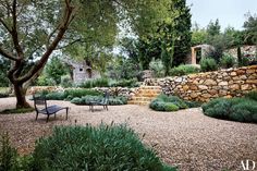 there is a bench in the middle of this garden with stone walls and trees around it