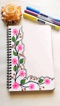 a notebook with flowers and two markers next to it