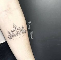 a small crown tattoo on the left arm