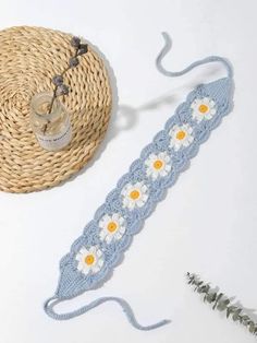 a crocheted headband with daisies on it next to a straw hat